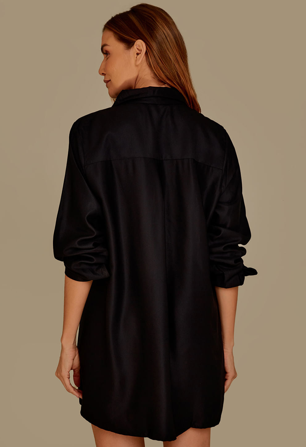 Vista traseira de camisão preto feminino de tecido liso com mangas longas, fundo bege neutro.
