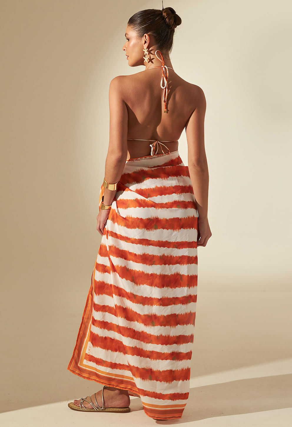 Top biquíni com argola Dunas laranja e branco com saia pareô combinando vista de costas em modelo feminino