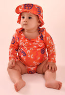 Bebê usando camisa manga longa laranja com estampa abstrata colorida e chapéu combinando