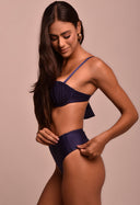 Modelo ajustando calcinha hot azul marinho de cintura alta e top de biquíni com franzidos.