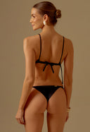 Mulher de costas usando biquíni preto acetinado com top de amarração e calcinha semi fio