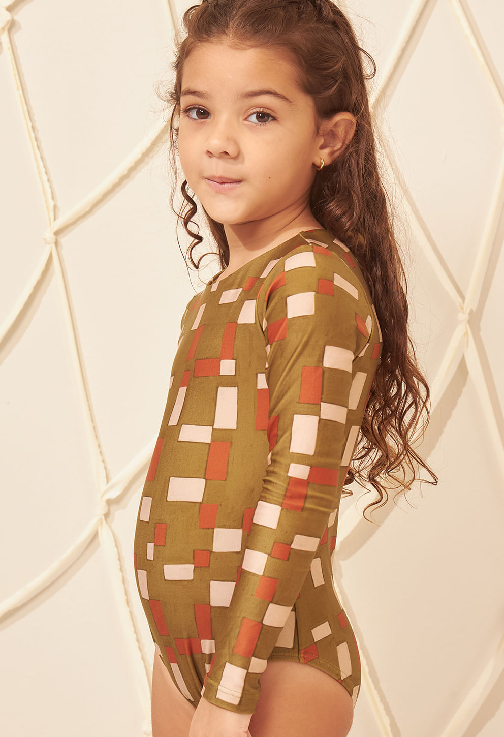 Maiô infantil verde oliva com padrão geométrico bege e laranja vista lateral, modelo mirim de perfil direito.