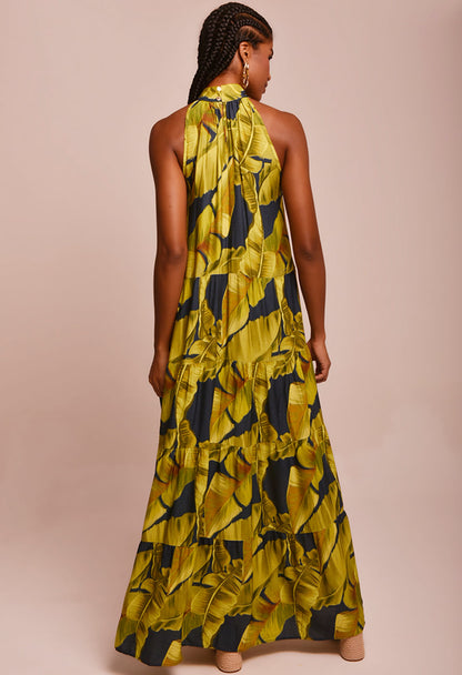 Vestido New Jasmin Quatro Folhas visto por trás, longo com estampa de folhas verdes e amarelas e gola alta