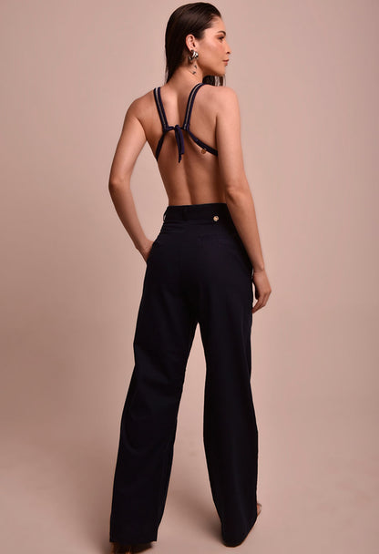 Mulher vista de costas usando calça pantalona azul marinho Malu Náutica e top de biquíni azul marinho.