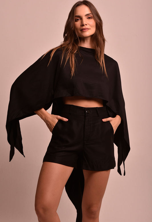 Blusa Lane Luar preta cropped com mangas largas e pontas soltas, usada com shorts preto