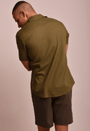 Vista traseira camisa de linho slim manga curta verde army masculina, modelo com bermuda marrom em fundo bege claro.