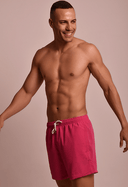 Bermuda masculina rosa Flor de Jambo vista frontal inclinada, modelo sorridente