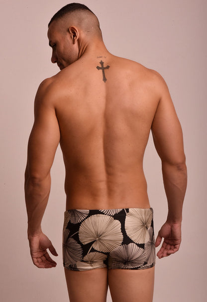 Vista traseira de homem usando sunga short adulto Sublime estampada com folhas bege e preto, fundo neutro.