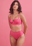 Mulher vestindo biquíni rosa pink com sutiã estruturado e calcinha hot pants em fundo rosa.
