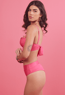 Mulher de perfil usando biquíni rosa pink acetinado com amarração nas costas e calcinha hot pants em fundo rosa.